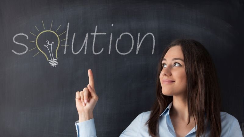 solution A woman in front of a blackboard, pointing up.
